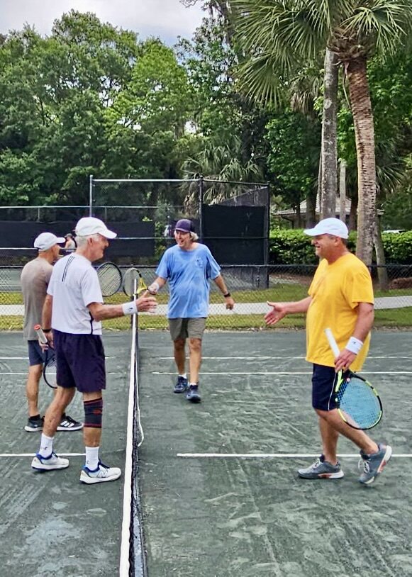 Doubles players shaking hands at the net after a match.