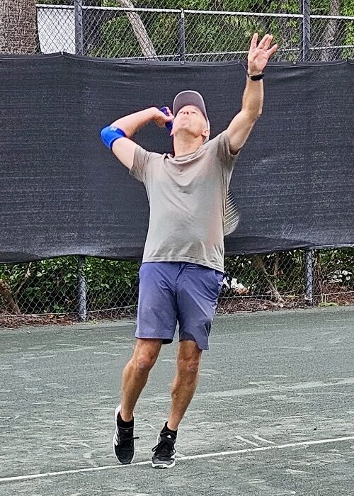 A player tossing the ball to serve on the tennis court.