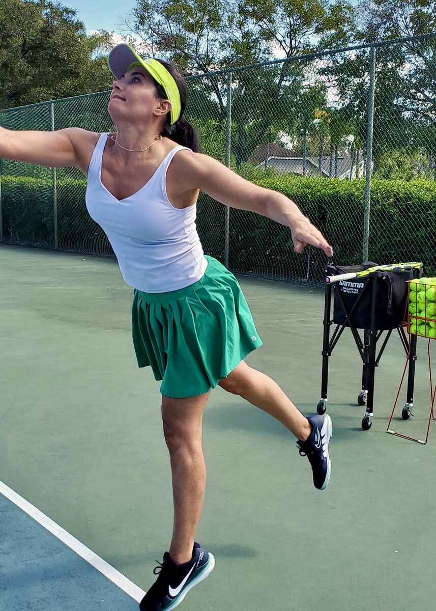 A player reaching up to serve on the tennis court.