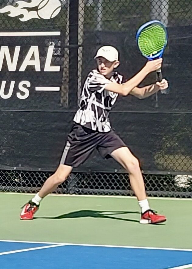 A young player hitting a forehand at a tournament.