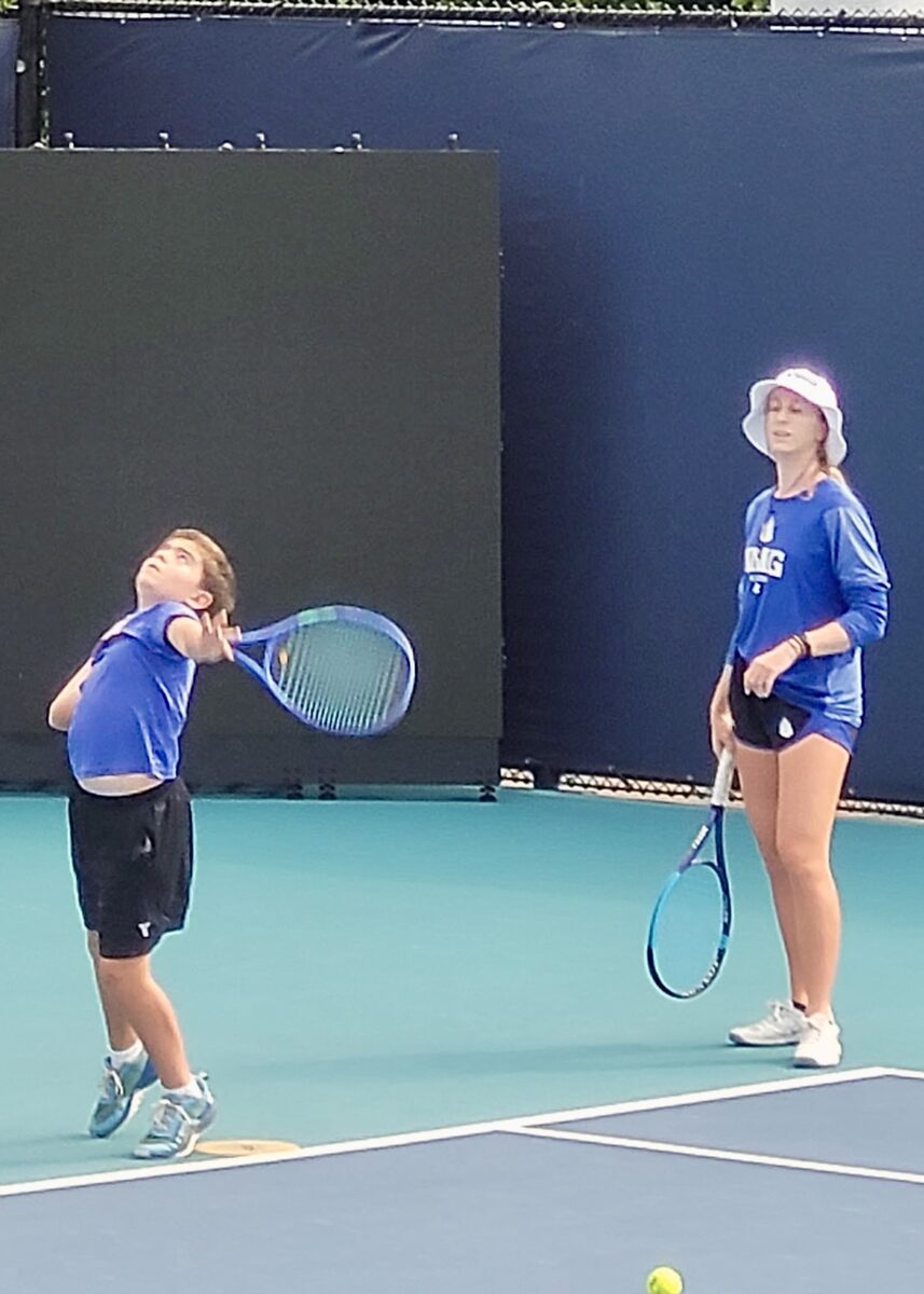 A young player serving during a doubles match.