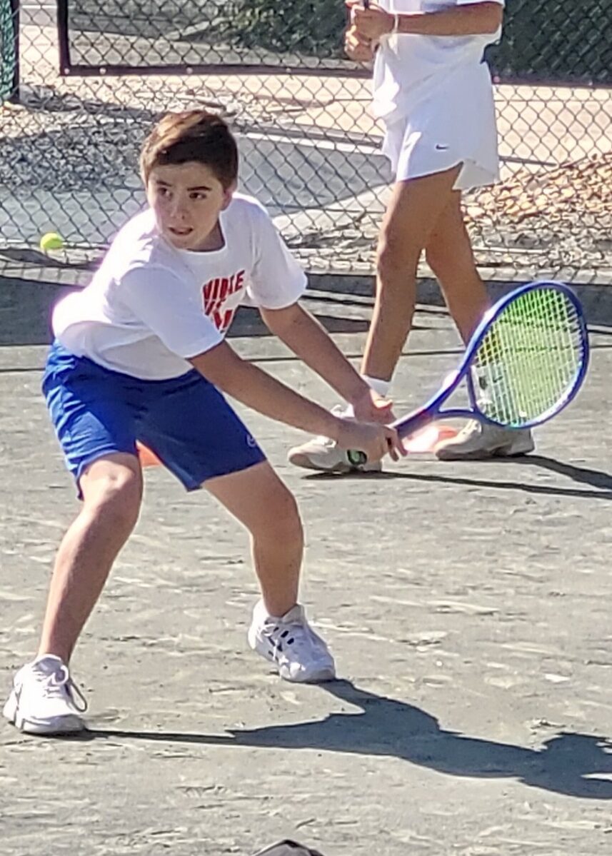 A junior player setting up a two-handed backhand.