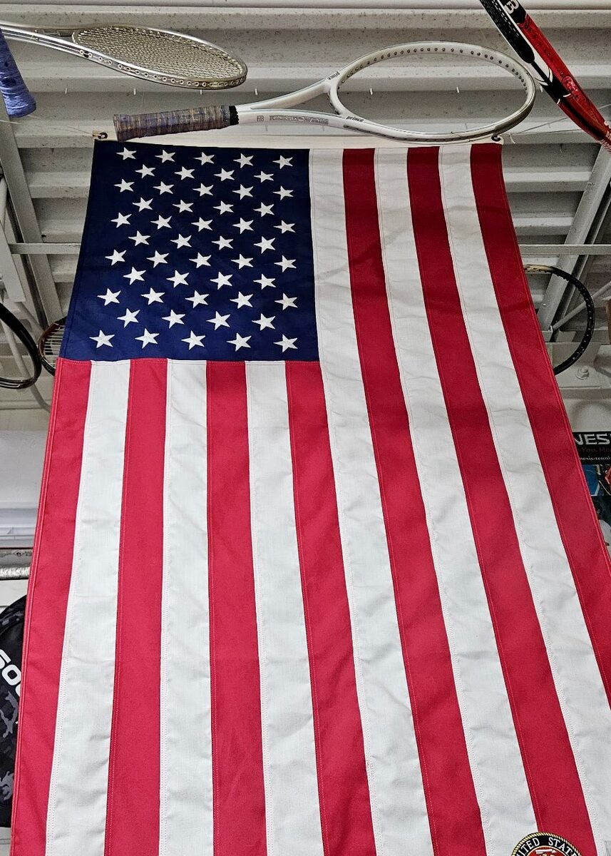 An American flag hanging in the shop beneath a row of racquets.