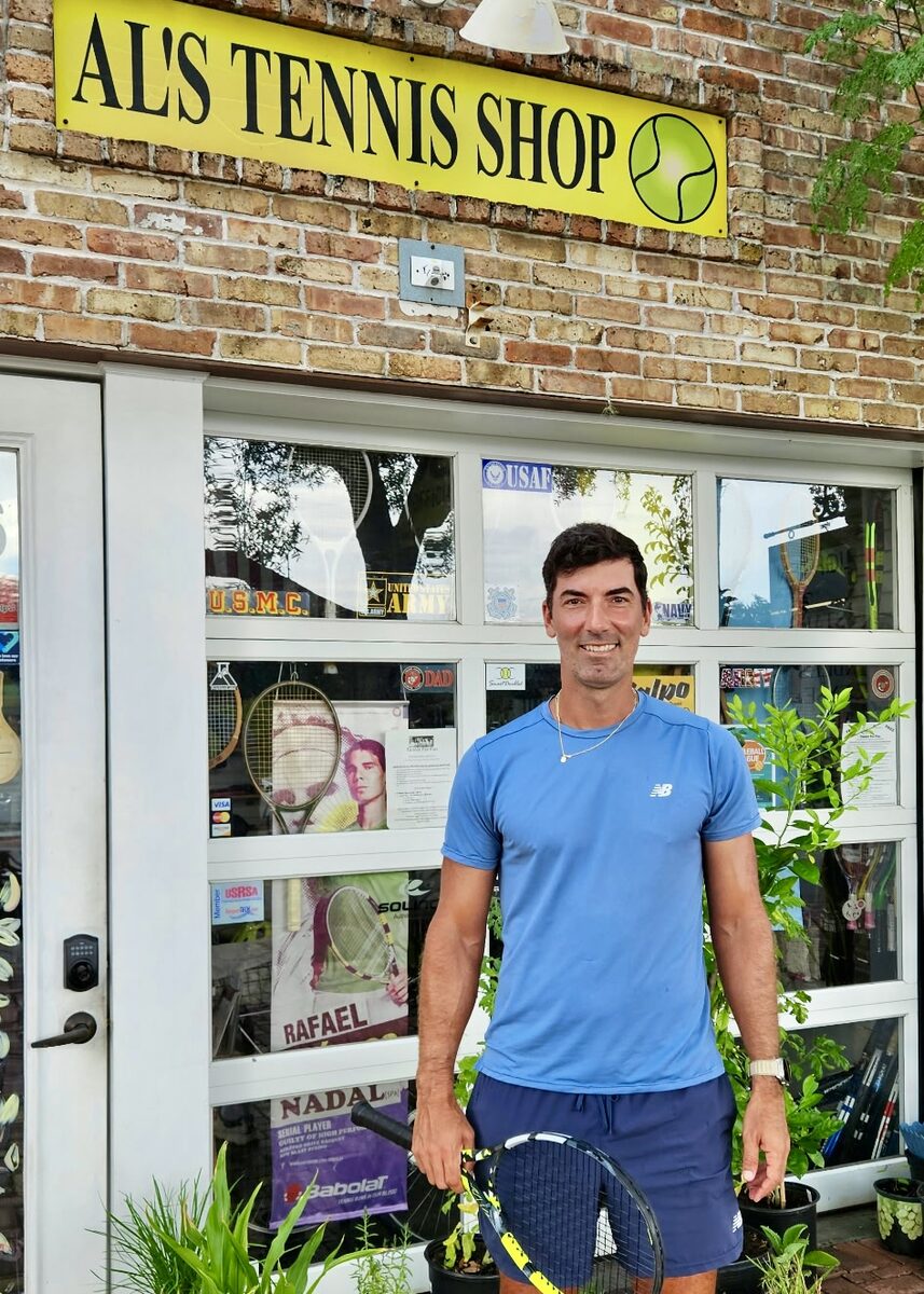 A customer with his racquet outside the front of Al's Tennis Shop.