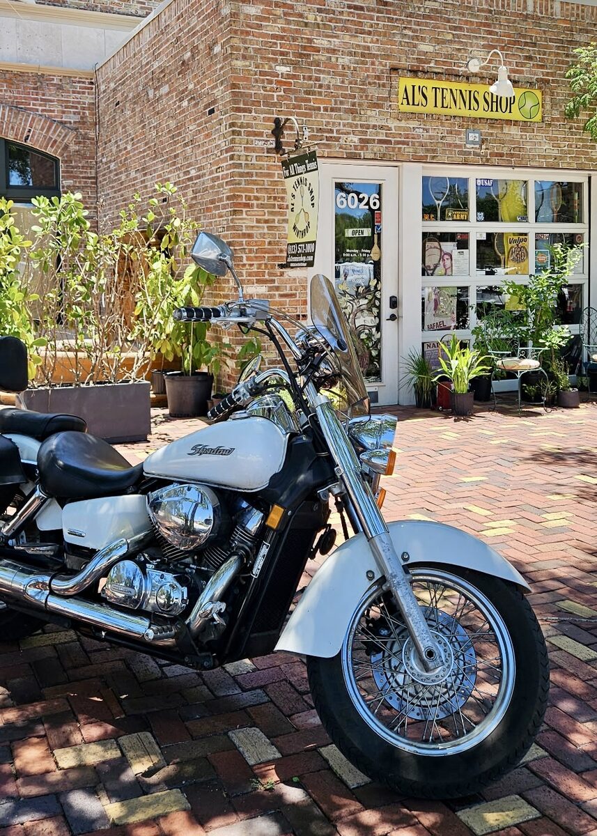 A motorcycle parked on the bricks outside Al's Tennis Shop.