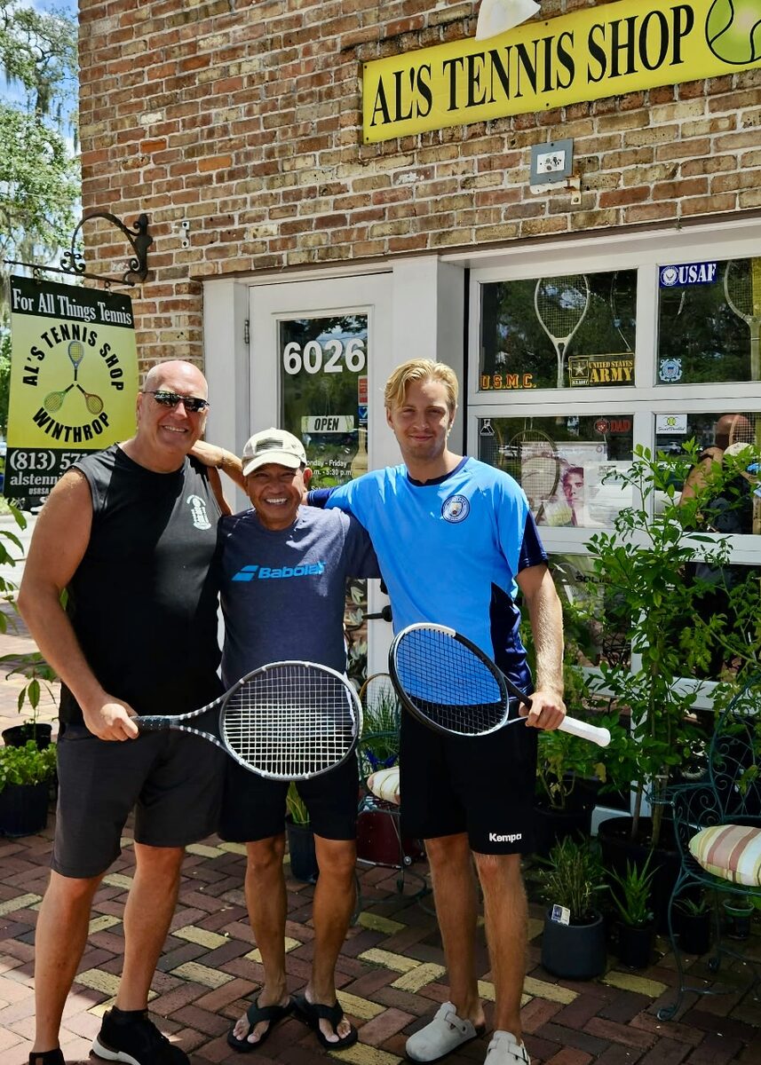 Three players together outside the front of Al's Tennis Shop.