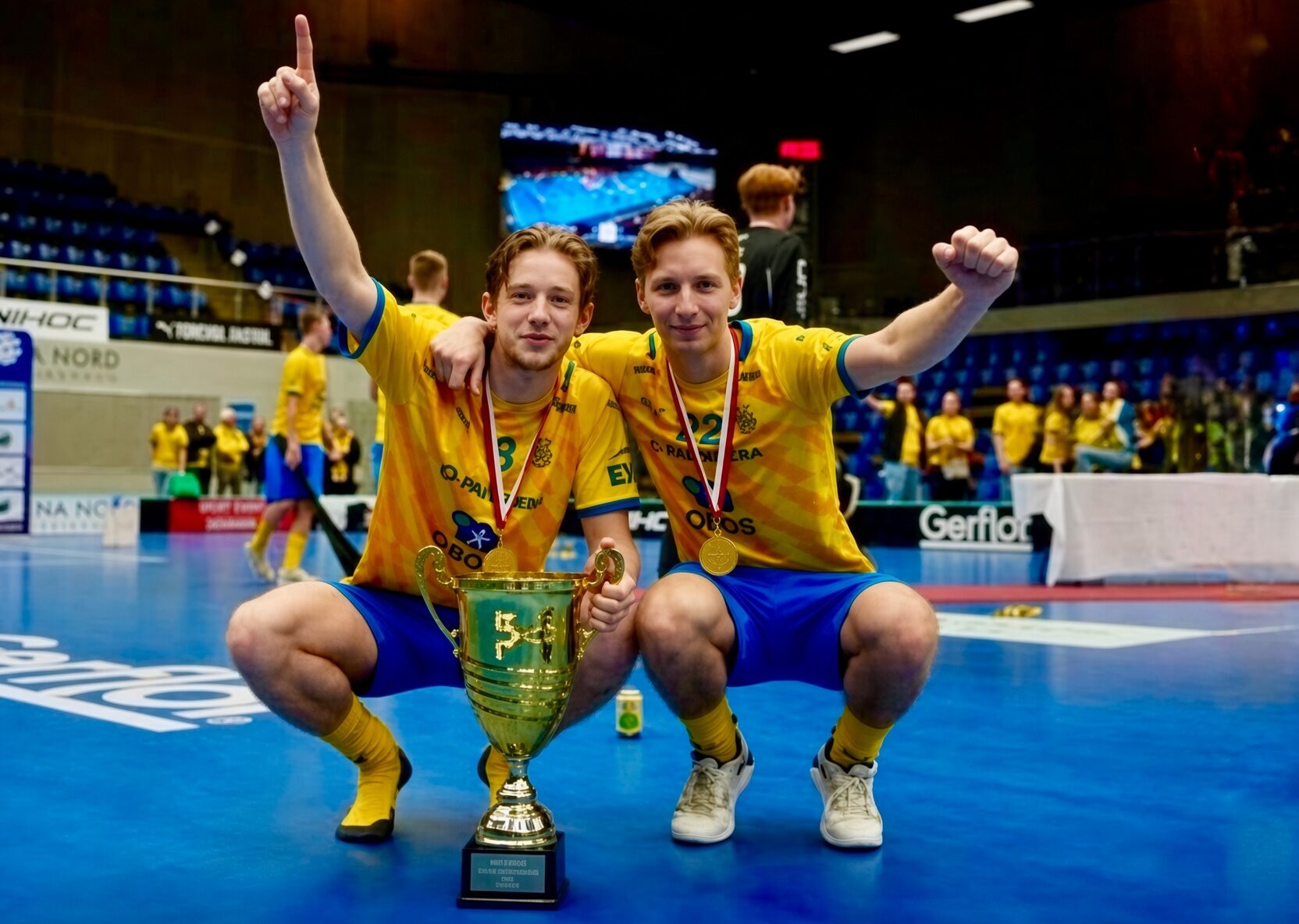 Two customers celebrating a championship win with a trophy and gold medals.