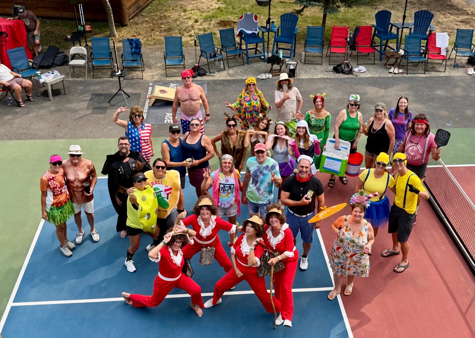 A big group of pickleball players in costume, posing together on the court for a dress-up day.