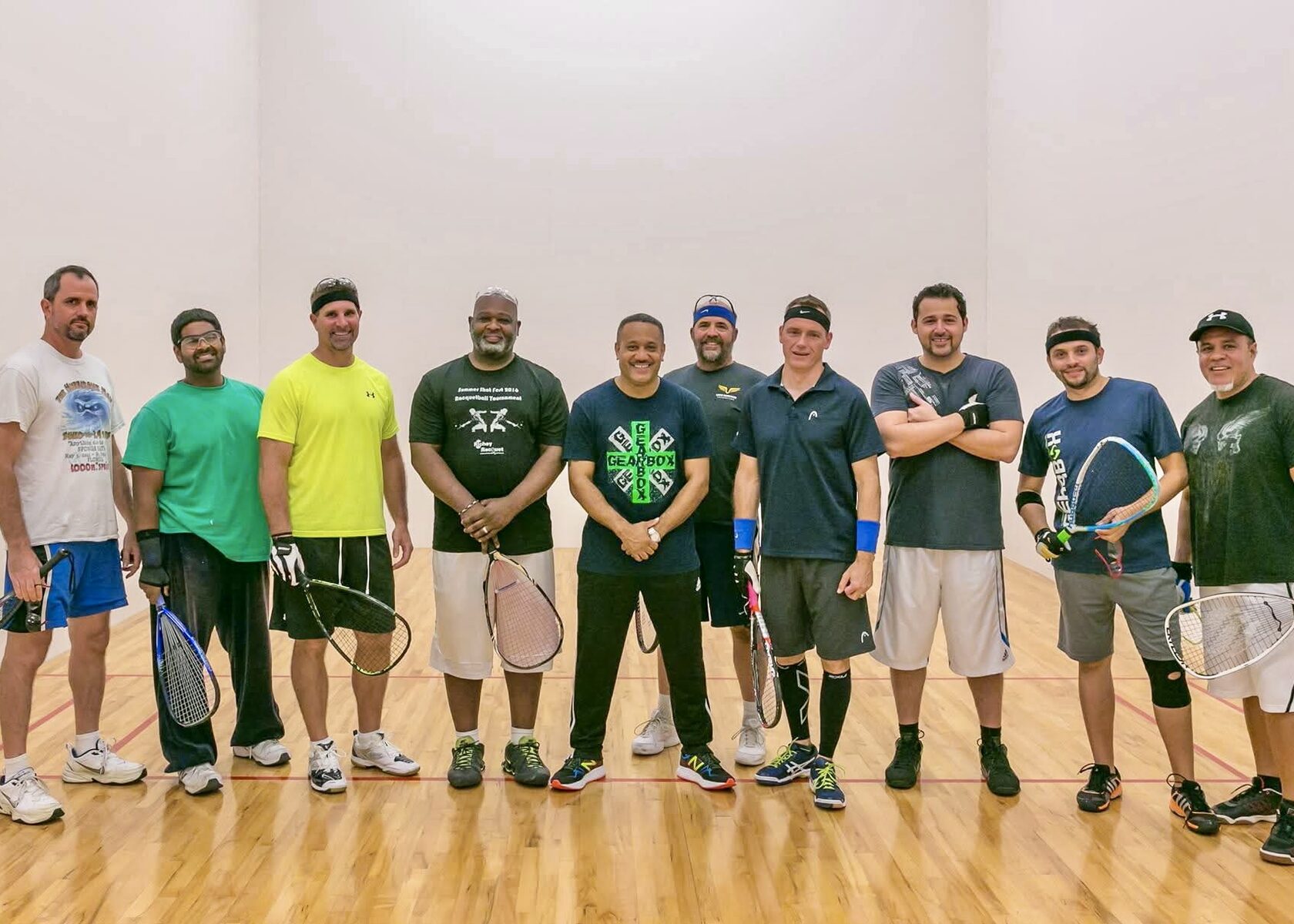 Ten racquetball players lined up on the court with their racquets.
