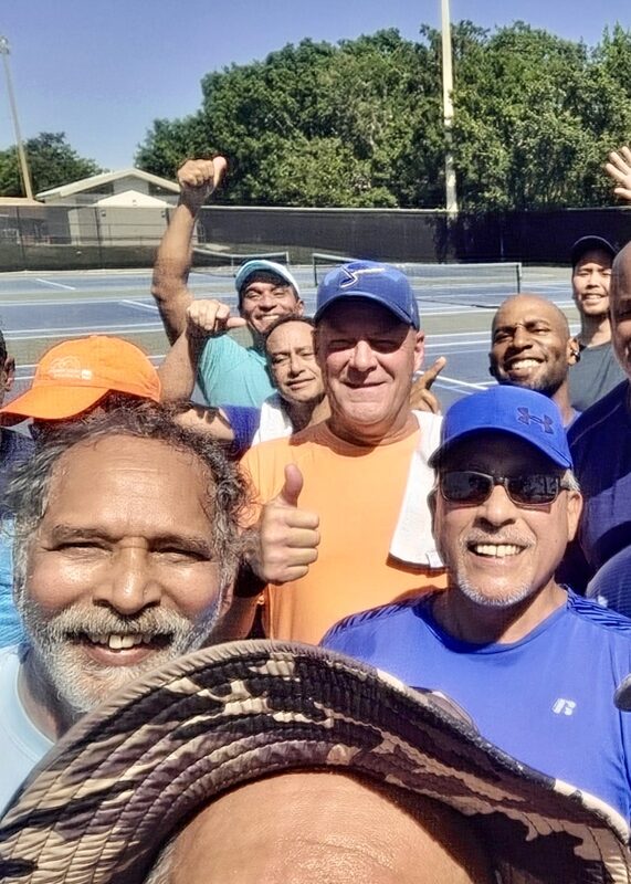 Local tennis players gathered on the courts for a group selfie, left side of the group.