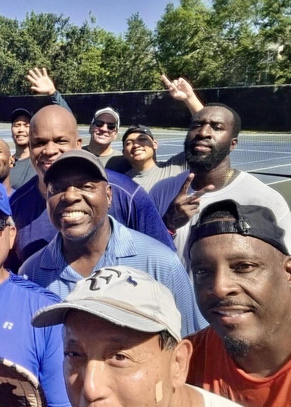 Local tennis players gathered on the courts for a group selfie, right side of the group.
